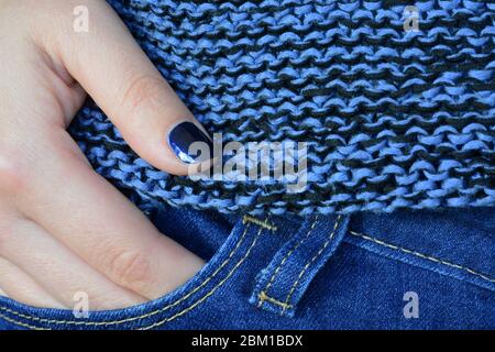 Classico colore blu tonalità. Donna che indossa jeans blu, maglione e smalto per unghie Foto Stock
