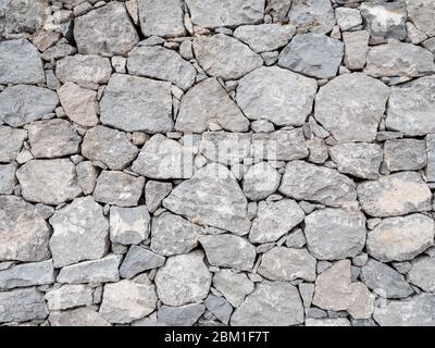 Muro di pietra secco. Il modello casuale di un muro di pietra piano e asciutto. Trama astratta di sfondo full frame. Foto Stock
