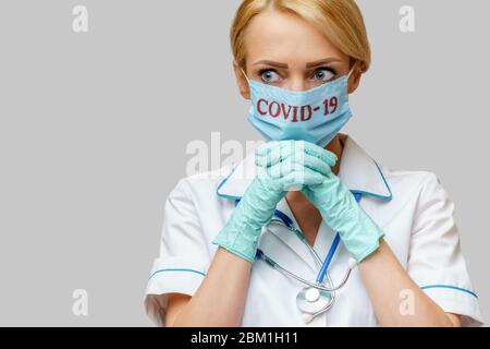 medico infermiere donna che indossa maschera protettiva e guanti in lattice - pregando nad sperando gesto Foto Stock