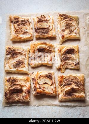 Dolci di pasta sfoglia di mela e cannella su una carta da forno stile piatto Foto Stock
