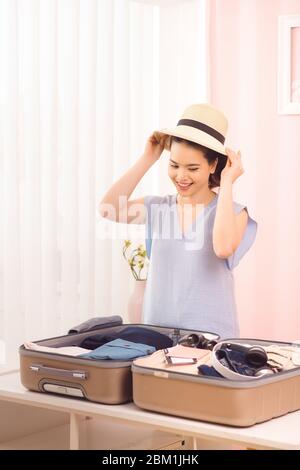 Giovani donne che scelgono cappello con vestiti e valigia. Prepararsi per le vacanze estive Foto Stock