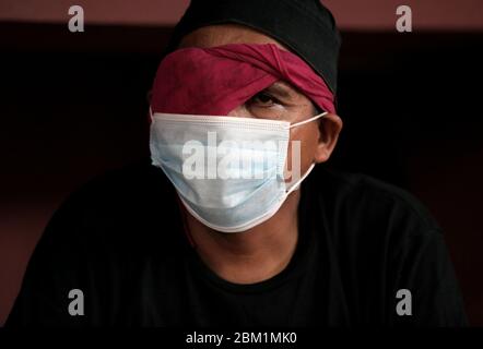 Un uomo senza casa indossa una maschera facciale come misura preventiva in un rifugio temporaneo tra COVID - 19 Coronavirus.Indonesia Ministero della Salute ha registrato un totale di 12,438 infezioni, morte 895 e 898 recuperati dall'inizio del focolaio. Foto Stock