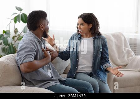 Furious African Woman urlando al suo ragazzo durante la discussione a casa Foto Stock