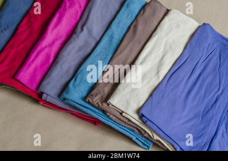 Un assortimento di t-shirt multicolore su un banco del negozio. Abbigliamento pratico realizzato con tessuti naturali per l'uso quotidiano. Primo piano. Vista dall'alto su a Foto Stock