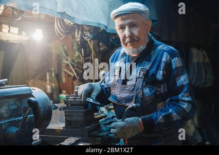 Meccanici anziani anziani per tornitore di sesso maschile che lavorano su macchine utensili per metallo Foto Stock