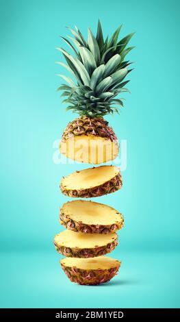 Flying fresco fette di ananas mature su sfondo blu Foto Stock