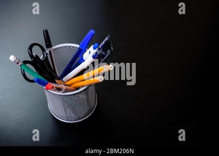 Stativo in metallo con matite, penne, forbici su tavolo in legno Foto Stock