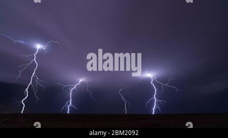 Intense cloud-to-ground lightning strikes ahead of a supercell thunderstorm near Goodland, Kansas Foto Stock