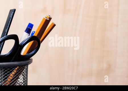Stativo in metallo con matite, penne, forbici su fondo in legno Foto Stock
