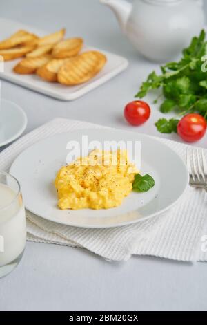 Uova strapazzate, Omelet. Colazione con uova fritte, bicchiere di latte, pomodori Foto Stock