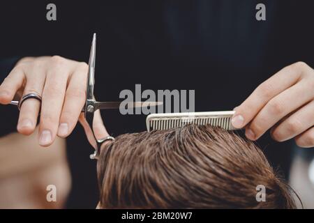 Barbiere, barbiere uomo in uomo parrucchiere fa i capelli con le forbici Foto Stock