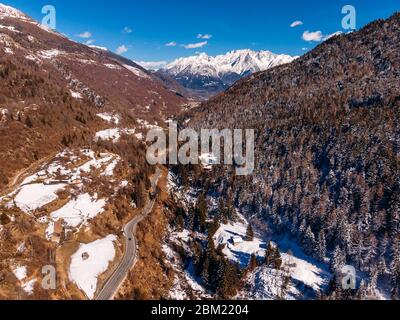 Strada tortuosa in montagna delle Alpi d'Italia. Giornata di sole. Vista dall'alto dell'antenna Foto Stock