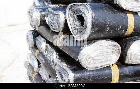 Primo piano di rotoli di nuovo feltro nero o bitume che viene piegato con precisione. Foto Stock