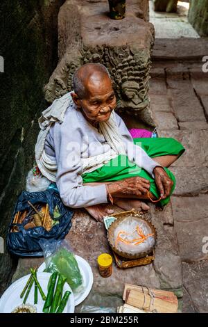 Una donna cambogiana anziana si prepara a dare una benedizione ai visitatori del Tempio di Preah Khan, del complesso del Tempio di Angkor Wat, Siem Reap, Cambogia. Foto Stock