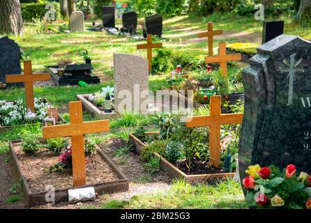 Tombe con lapidi e croci in legno in un cimitero Foto Stock