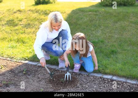 Mamma e figlia lavorano in zoccoli in un giardino Foto Stock