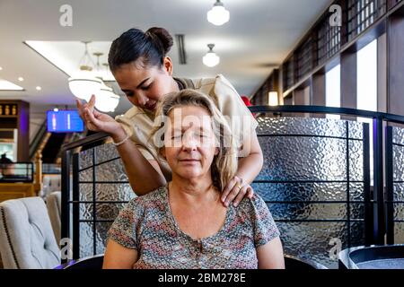 Una viaggiatore femminile che ha UN massaggio gratuito in una lounge dell'Aeroporto Internazionale di Bangkok, Thailandia. Foto Stock