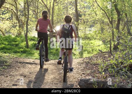 Le ragazze teenage che cavalcano le bici sul percorso attraverso i boschi Foto Stock