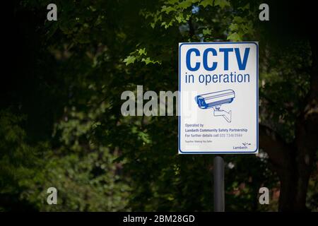 Il cartello "CCTV in Operation" è circondato da verde vegetazione di alberi, Streatham, Londra, Inghilterra, Regno Unito Foto Stock