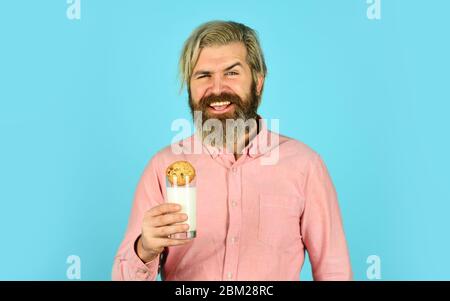 Ammollo di biscotto sul latte. Felice agricoltore mangia dessert di biscotto. Bearded uomo beve latte utile con pasticceria. Cibo e bevande di Natale. Biscotti e latte di Natale. Freddo Natale concetto di coziness. Foto Stock