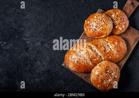 Pane integrale e panini fatti in casa con semi di lino e sesamo su Dark Table. Visualizzazione dall'alto piatto. Spazio copia Foto Stock