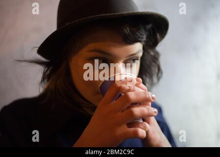 Una ragazza in un cappello sta aspettando qualcuno di notte in una stazione ferroviaria, una foto scattata su nastro, film grano Foto Stock