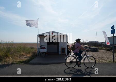 Una donna di mezza età che pedala lungo il percorso ciclabile che corre lungo la parte anteriore da Deal a Walmer e Kingsdown, Kent, Regno Unito Foto Stock