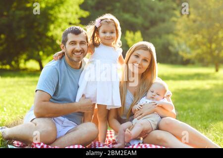 Famiglia felice seduto sul verde erba stanno giocando nel parco.il concetto di una famiglia felice. Foto Stock