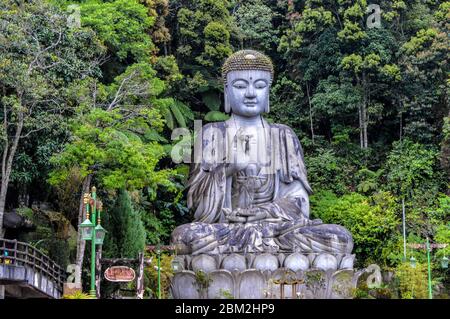 Una grande statua di Buddha si trova su un bordo di montagna nelle Genting Highlands a Pahang, Malesia. Il Tempio delle Grotte di Chin Swee si trova a Genting Highland. Foto Stock