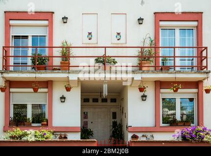 Una casa esterna con grande balcone, fiori colorati e vasi da fiori. Foto Stock