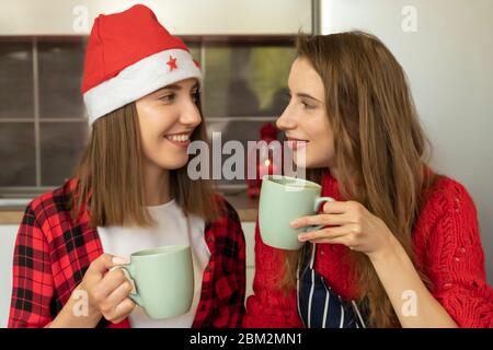 Due ragazze stanno preparando i biscotti di Natale a casa nella cucina. Scherzano e si divertono, godono le faccende di vacanza. Foto Stock