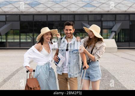 Una compagnia di giovani, felici turisti alla stazione ferroviaria. Gli amici si rallegrano per le vacanze e i viaggi. Foto Stock