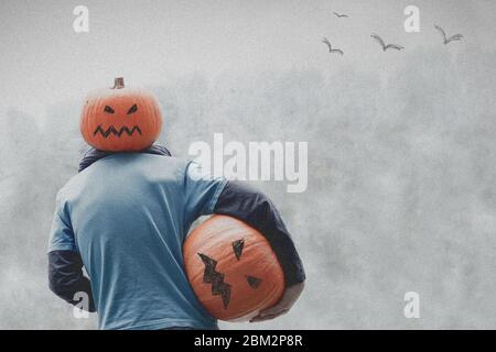halloween - zucca con testa di zucca e zucca in mano. Grigio e terribile Foto Stock