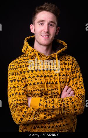 Felice giovane uomo bello indossare hoodie con le braccia incrociate Foto Stock