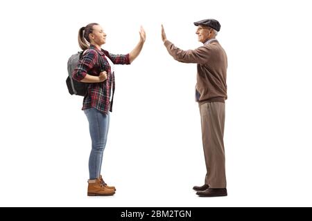 Foto di profilo a tutta lunghezza di una studentessa che accoglie un anziano con un alto-cinque isolati su sfondo bianco Foto Stock