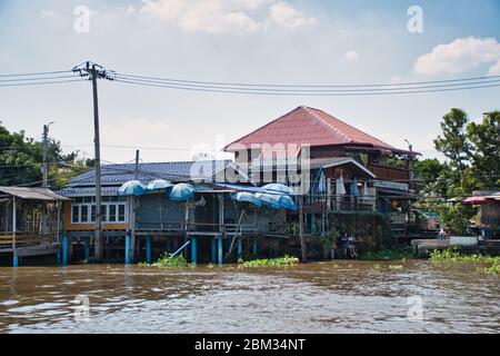 Bangkok, Thailandia 01.04.2020: Case thailandesi con architettura tradizionale, segni, simboli sulla riva del fiume Chao Phraya Foto Stock