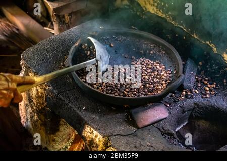 Vecchia donna balinese torrefazione caffè chicchi con metodo tradizionale Foto Stock