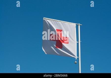 Bandiera della Croce Rossa Internazionale e movimento della Mezzaluna Rossa contro un cielo blu a Manno, Svizzera. La Croce Rossa è un'opera umanitaria internazionale Foto Stock