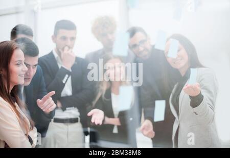 giovane donna di affari che incolla la nota adesiva sulla parete di vetro. Foto Stock