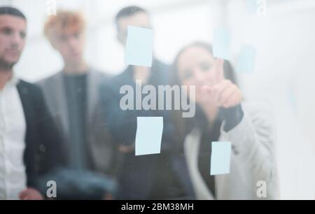giovane donna di affari che incolla la nota adesiva sulla parete di vetro. Foto Stock