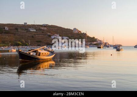 Pomeriggio sull'isola di Kea in Grecia. Un piccolo porto e una vecchia barca da pesca in primo piano. E' ora d'oro e il mare è tranquillo. Foto Stock