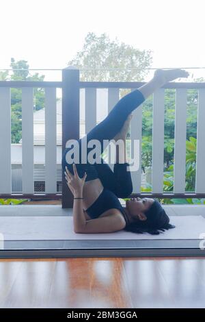 giovane donna che fa yoga su tappetino yoga a casa Foto Stock