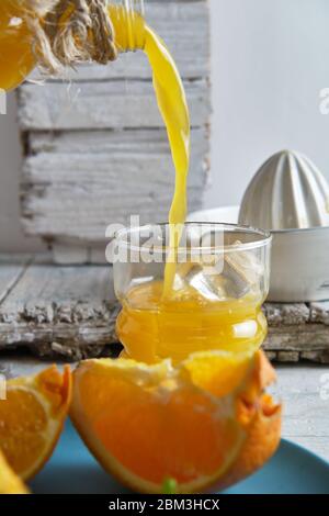 succo d'arancia appena fatto in uno spremiagrumi in ceramica, versato in un cristallo Foto Stock