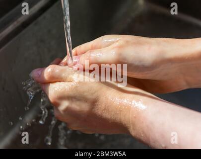 Donna lavando le mani con sapone per prevenire germi, batteri ed evitare infezioni da coronavirus Foto Stock