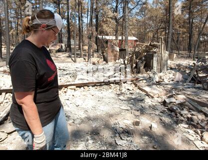 Bastrop Texas USA, settembre 2011: La famiglia passa attraverso la casa danneggiata dopo massicci incendi boschivi spazzati attraverso quartieri boscosi, bruciando più di 1400 case nella zona all'inizio di settembre. ©Marjorie Kamys Cotera/Daemmrich Photography Foto Stock