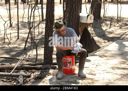 Bastrop Texas USA, settembre 2011: La famiglia passa attraverso la casa danneggiata dopo massicci incendi boschivi spazzati attraverso quartieri boscosi, bruciando più di 1400 case nella zona all'inizio di settembre. ©Marjorie Kamys Cotera/Daemmrich Photography Foto Stock