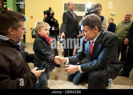 Waukee, Iowa USA, 3 gennaio 2012: Texas Gov. Rick Perry, candidato alla nomina presidenziale repubblicana, si inginocchia per scuotere la mano di un giovane ragazzo prima dell'apparizione di una campagna elettorale. ©Bob Daemmrich Foto Stock