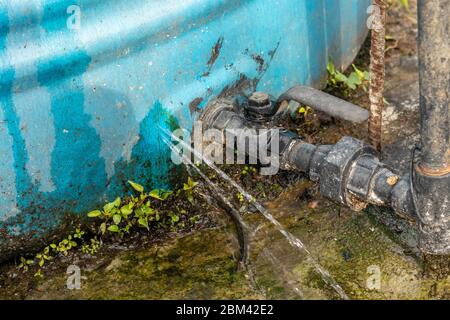 Perdite di acqua da incrinature nel serbatoio dell'acqua installato sul tetto della casa. Foto Stock