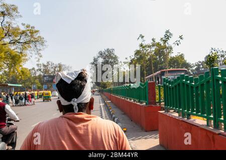 New Delhi, India - Feb, 2019. Uomo risciò indossando un panno bianco sulla testa, guidando il risciò manuale su strada. Foto Stock