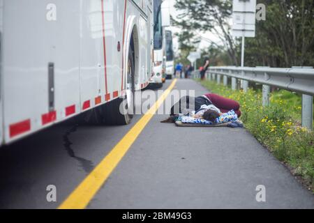 Una persona che dorme per le strade di Bogota in attesa di tornare nel suo paese, il Venezuela, a causa della diffusione del virus della corona pandemica, COVID-19 Foto Stock